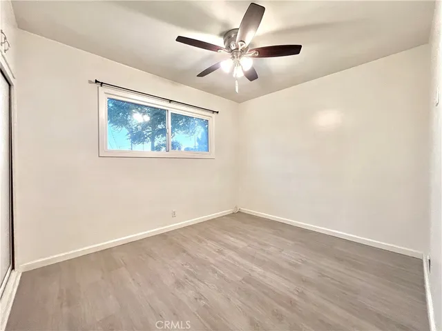 an empty room with wooden floor ceiling fan and windows