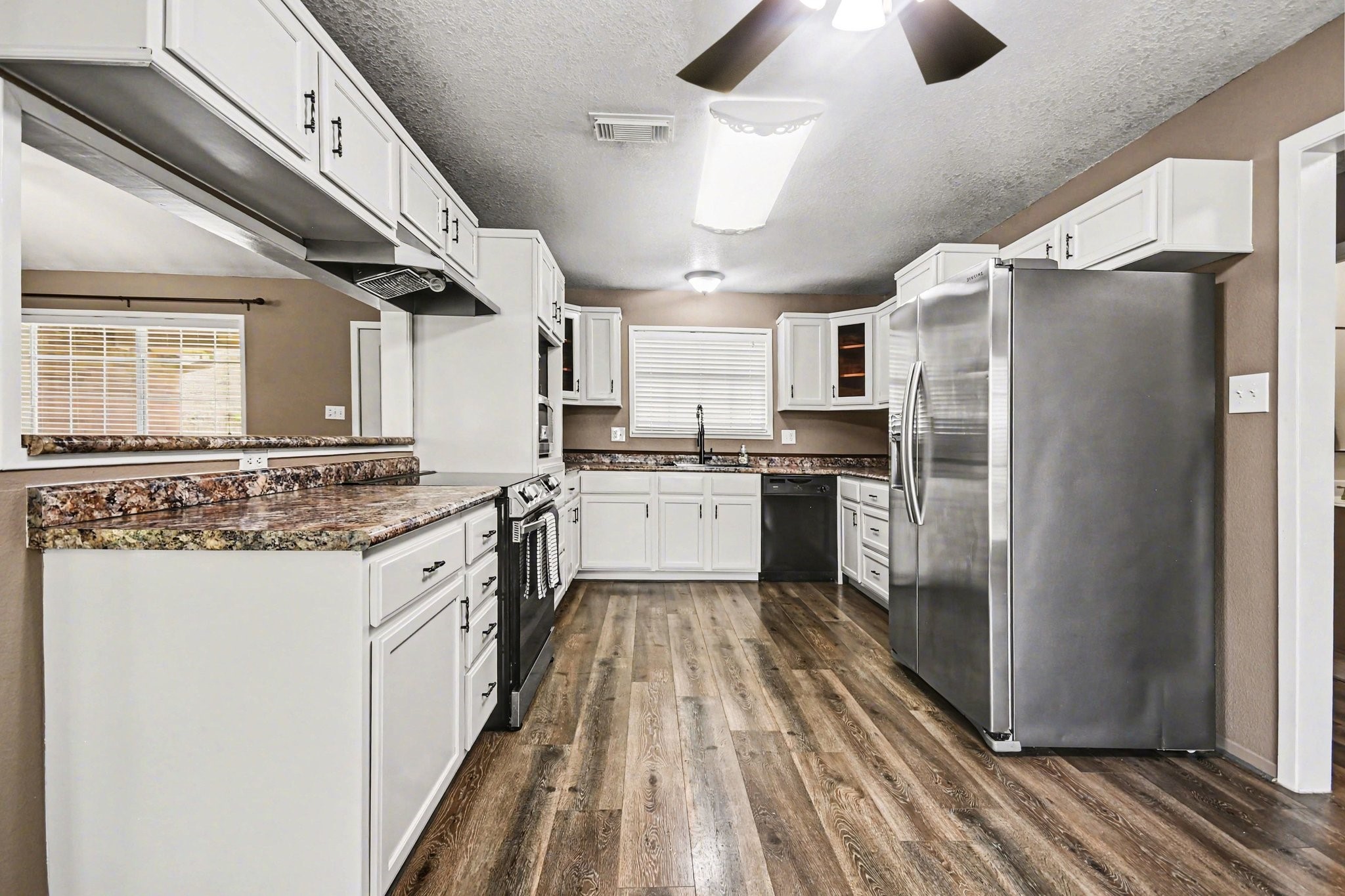 21503 Pecan Bend Road Damon, TX 77430 - Photo 12 of 45 a kitchen with granite countertop a refrigerator a sink a stove and white cabinets