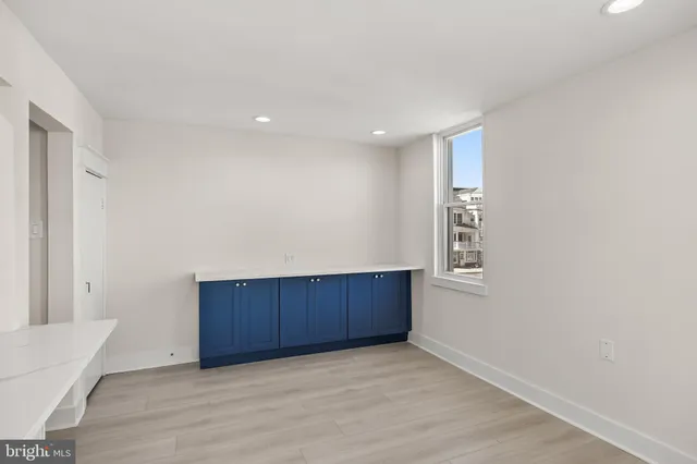 a view of an empty room with wooden floor and a cabinet