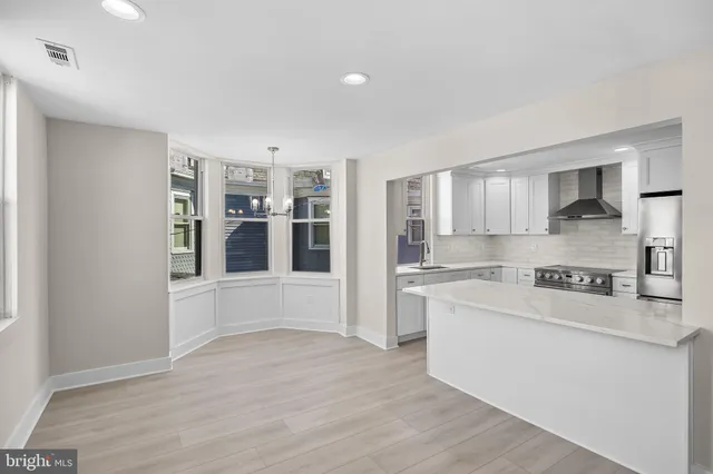 a large white kitchen with kitchen island a sink a stove and a refrigerator