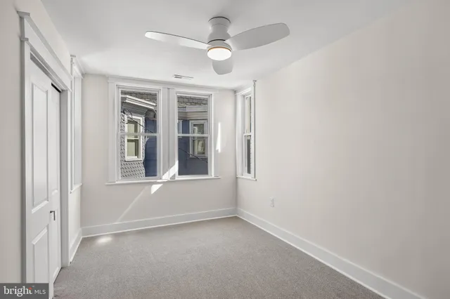 an empty room with windows and fan