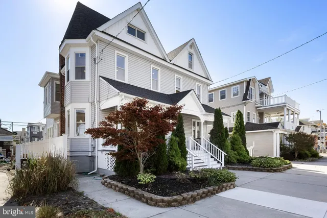 a view of a white building among the street with palm trees