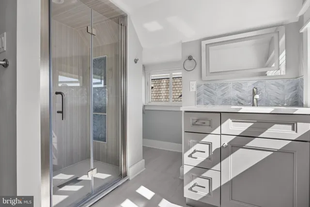 a bathroom with a granite countertop sink a mirror and shower