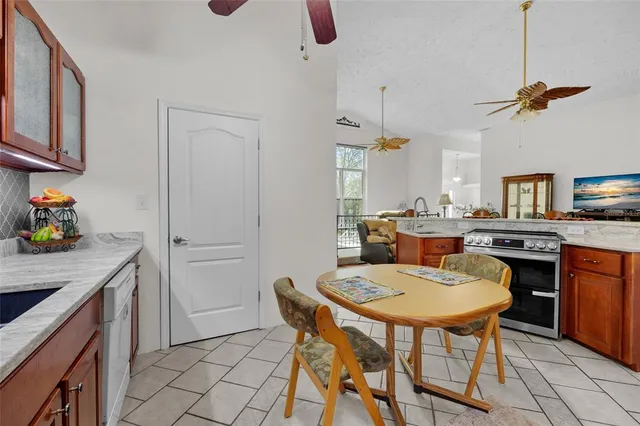 a kitchen with stainless steel appliances a dining table chairs stove and white cabinets