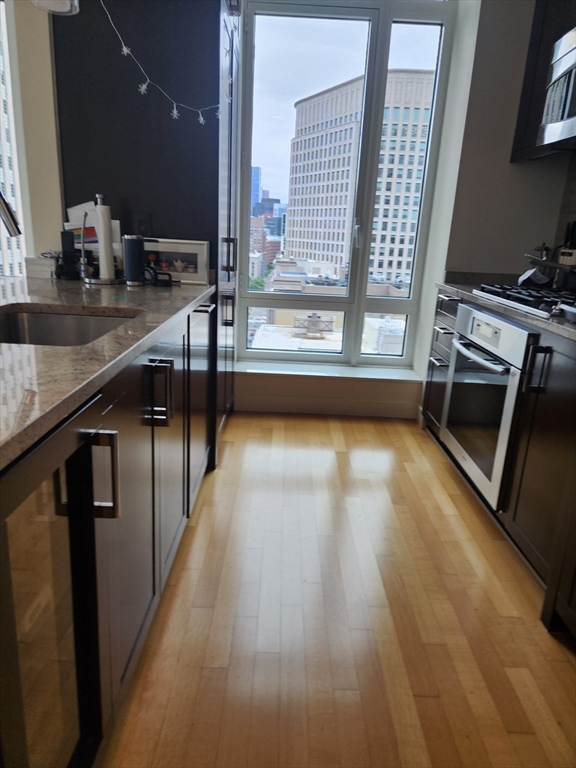 400 Stuart Street, Unit 18K Boston, MA 02116 - Photo 12 of 31 a view of a kitchen with kitchen island a sink wooden floor and a counter top space