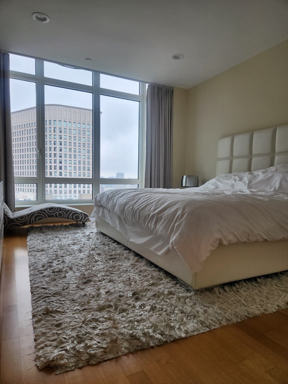 400 Stuart Street, Unit 18K Boston, MA 02116 - Photo 18 of 31 a spacious bedroom with a bed and wooden floor