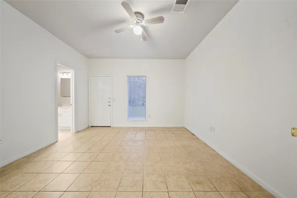 an empty room with a ceiling fan and a window