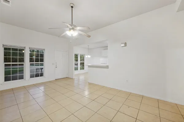 a view of an empty room with a window and kitchen view