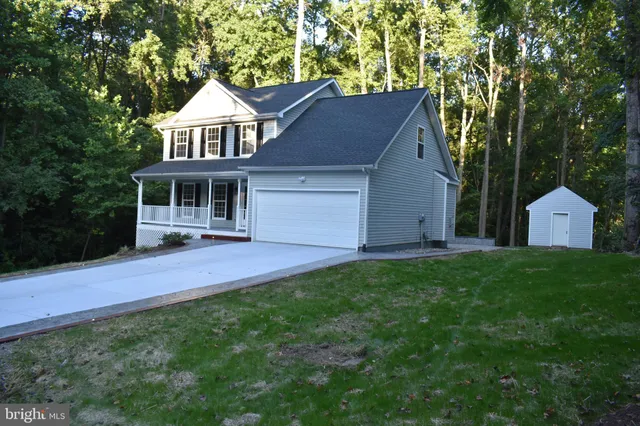 a view of a house with a yard and large tree
