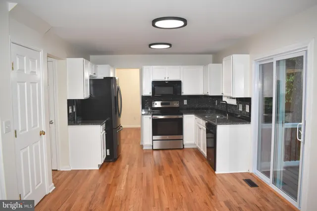 a kitchen with a refrigerator a stove top oven a sink and dishwasher with wooden floor