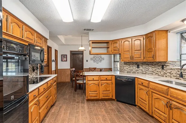 a kitchen with stainless steel appliances granite countertop hardwood floor sink stove dining table and chairs