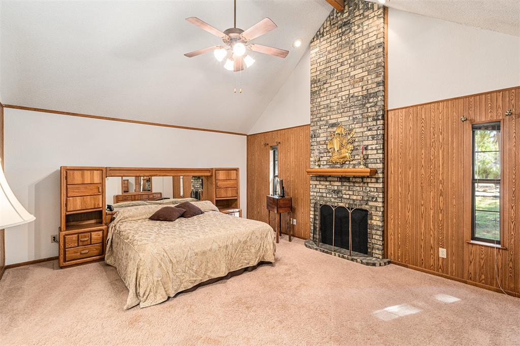 1199 Cedar Lane Kaufman, TX 75142 - Photo 18 of 40 Bedroom with wood walls, carpet flooring, high vaulted ceiling, a fireplace, and ceiling fan
