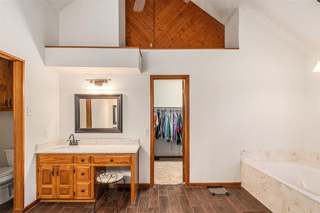 1199 Cedar Lane Kaufman, TX 75142 - Photo 21 of 40 Primary full bath featuring a spacious closet, wood tiled floors, vanity, a textured ceiling, and a garden tub