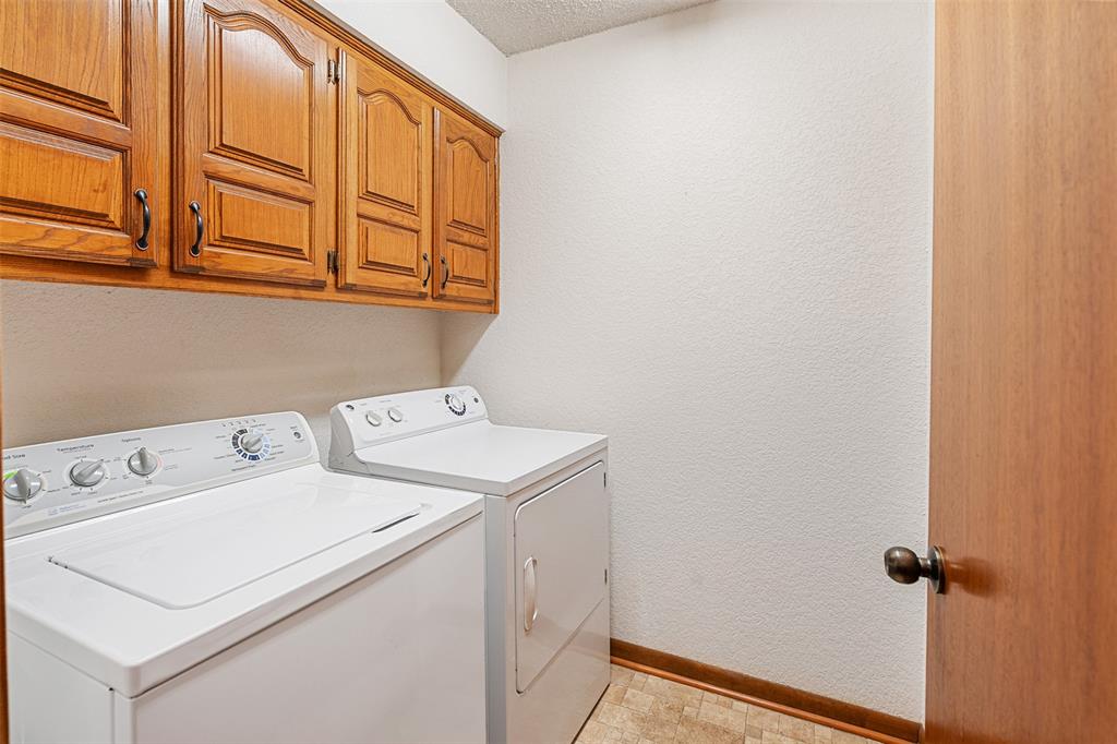 1199 Cedar Lane Kaufman, TX 75142 - Photo 30 of 40 Laundry room featuring a textured wall, washing machine and clothes dryer, cabinet space, and a textured ceiling