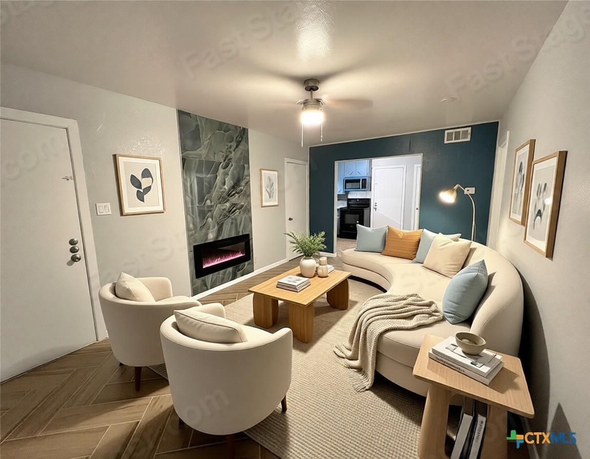 Living room featuring a high end fireplace and a ceiling fan