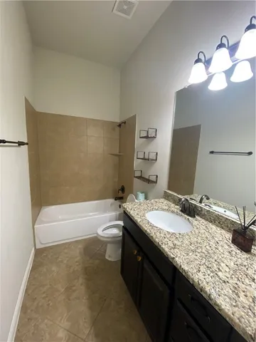 a bathroom with a granite countertop sink a toilet and bathtub