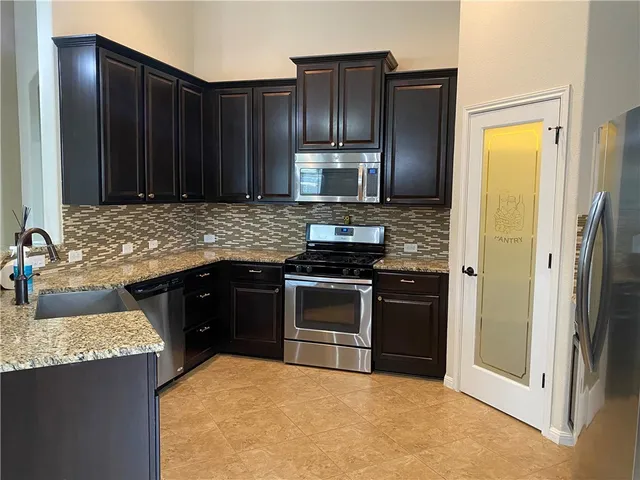 a kitchen with granite countertop wooden cabinets and stainless steel appliances