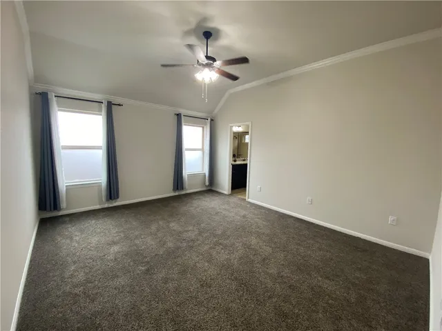 an empty room with chandelier fan and windows