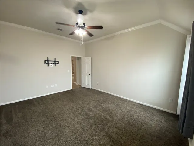 an empty room with a chandelier fan and windows