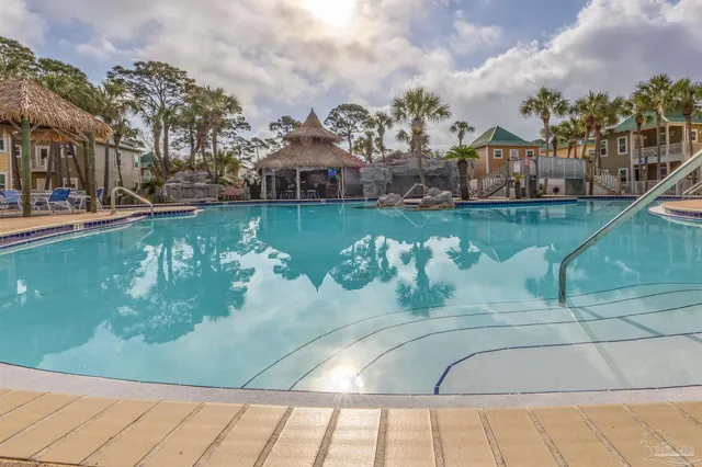a view of a swimming pool with a table and chairs under an umbrella