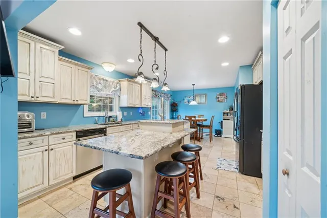 a kitchen with stainless steel appliances granite countertop a table chairs sink and cabinets