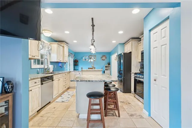 a kitchen with stainless steel appliances kitchen island granite countertop a refrigerator and a sink