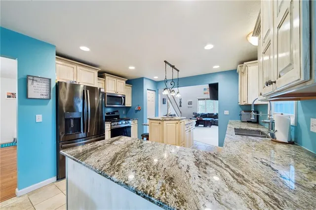 a kitchen with stainless steel appliances kitchen island granite countertop a refrigerator and a sink