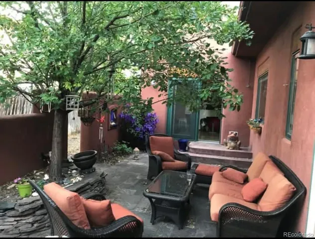 a view of a patio with table and chairs potted plants and a large tree