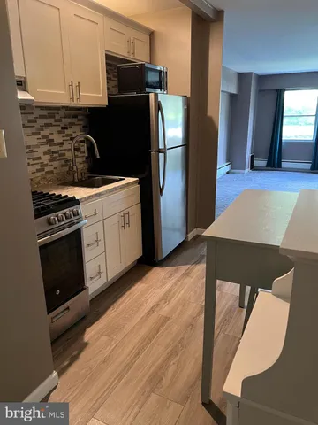 a kitchen with granite countertop a refrigerator stove and cabinets