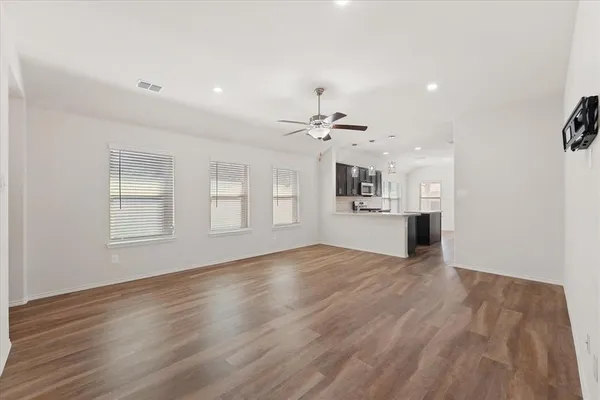 a view of an empty room with window and wooden floor