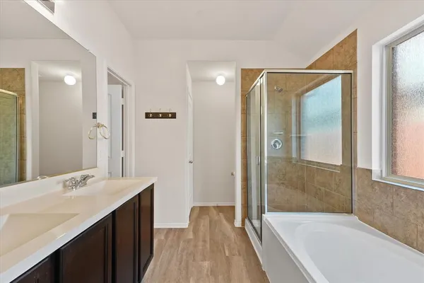 a bathroom with a tub shower vanity and a sink
