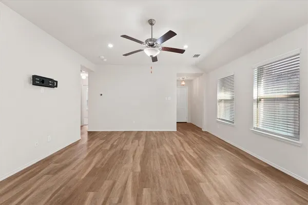 a view of empty room with wooden floor and fan