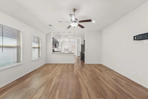 a view of an empty room with window and wooden floor