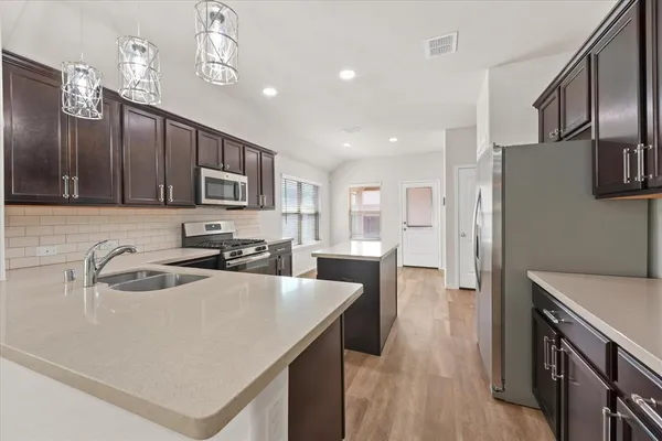 a kitchen with a refrigerator a sink a stove and cabinets