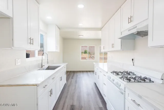 a kitchen with granite countertop a sink stove and cabinets