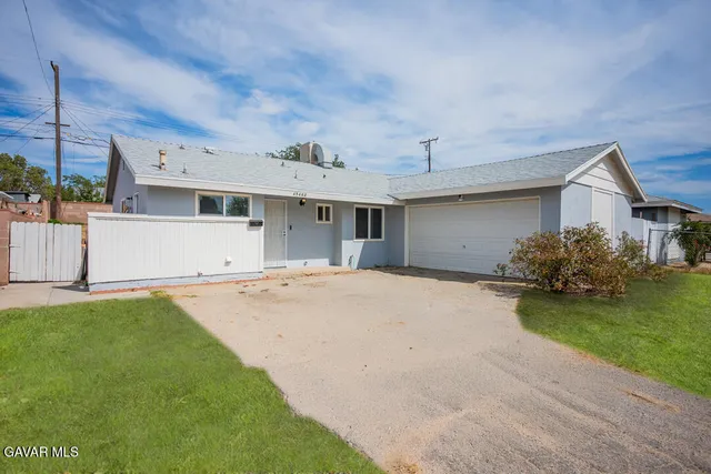 a view of a white house next to a yard with potted plants
