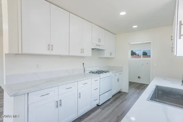 a kitchen with granite countertop white cabinets and a sink