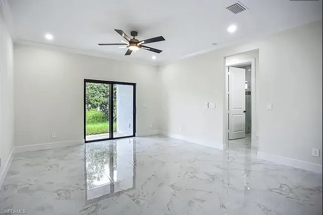 an empty room with windows and ceiling fan
