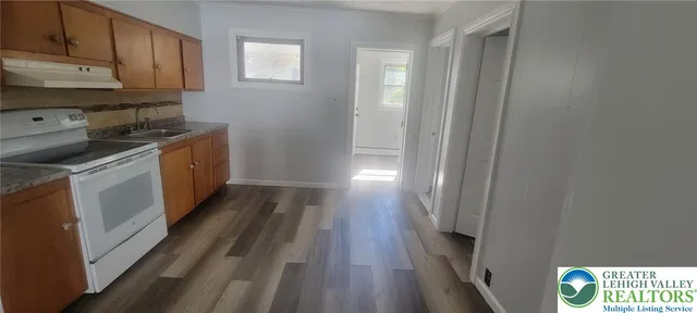 a kitchen with wooden floor and electronic appliances