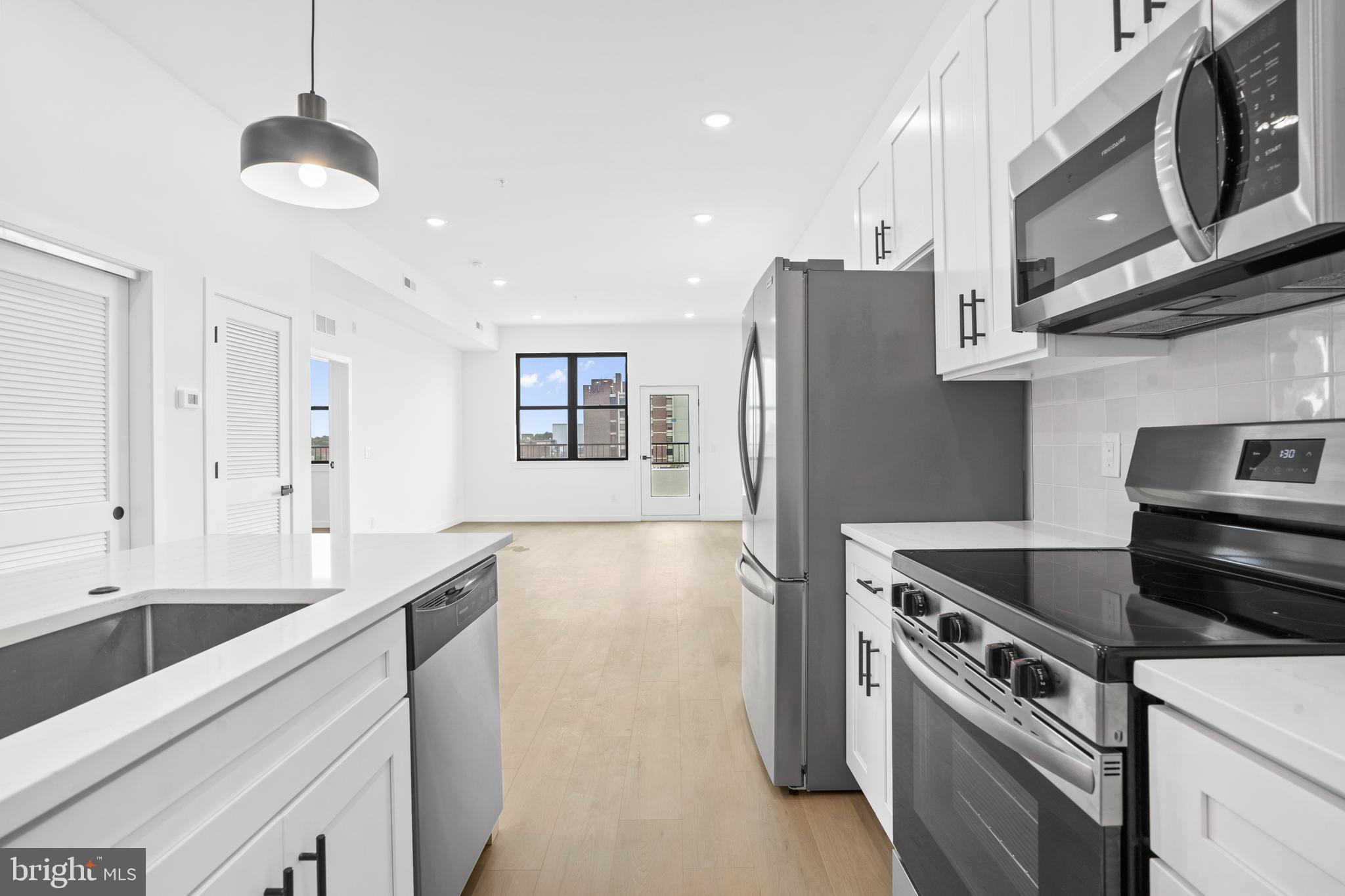 3211 Cedar Street, Unit 401 Philadelphia, PA 19134 - Photo 2 of 18 a kitchen with stainless steel appliances granite countertop a refrigerator a stove and a sink with wooden floor