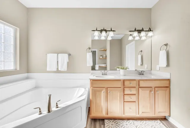 a bathroom with a tub sink and mirror
