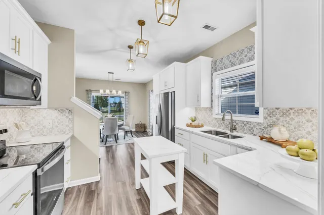 a large kitchen with a stove a sink dishwasher a dining table and chairs with wooden floor