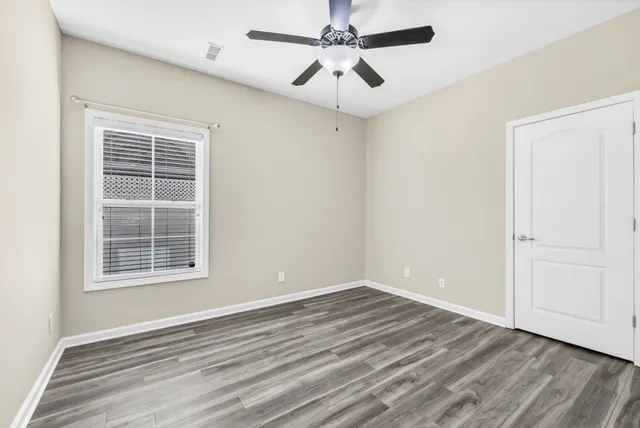 a view of empty room with wooden floor and fan