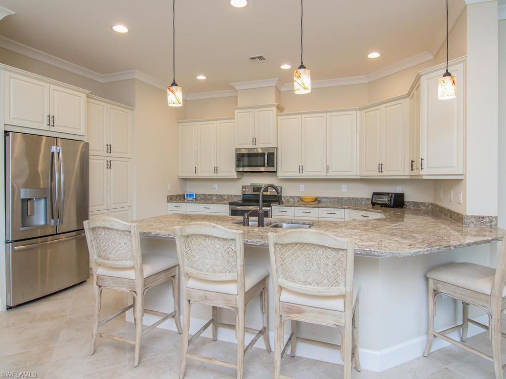 7002 Dominica Drive Naples, FL 34113 - Photo 3 of 33 a kitchen with kitchen island granite countertop a table chairs stainless steel appliances and cabinets