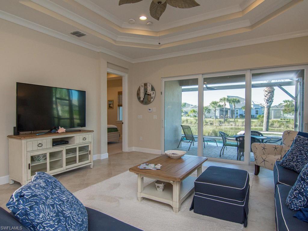 7002 Dominica Drive Naples, FL 34113 - Photo 8 of 33 a living room with furniture a flat screen tv and floor to ceiling window