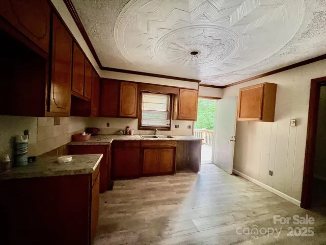 a large kitchen with stainless steel appliances granite countertop a refrigerator a sink dishwasher a stove and a dining table with wooden floor