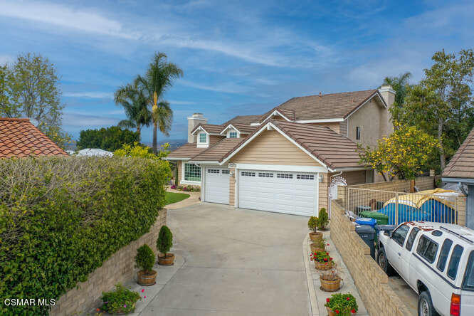 a view of a house with a small yard and a large tree