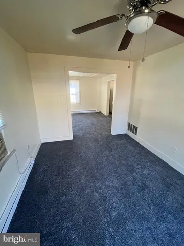 a view of a room with a ceiling fan and hardwood floor
