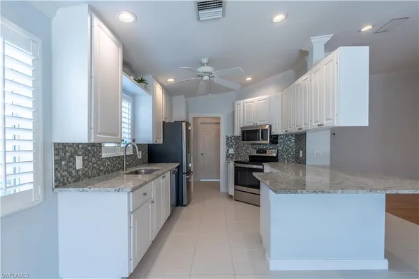 a modern kitchen with stainless steel appliances granite countertop a stove a sink a refrigerator and a oven
