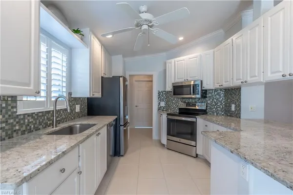 a kitchen with stainless steel appliances granite countertop a sink a stove a refrigerator a center island and cabinets